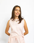 Woman wearing a light pink sleeveless top and shorts set on a white background