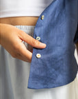 Close-up of a person buttoning a blue shirt with a blurred background