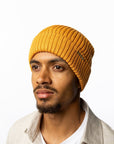 Man wearing a mustard yellow beanie on a white background