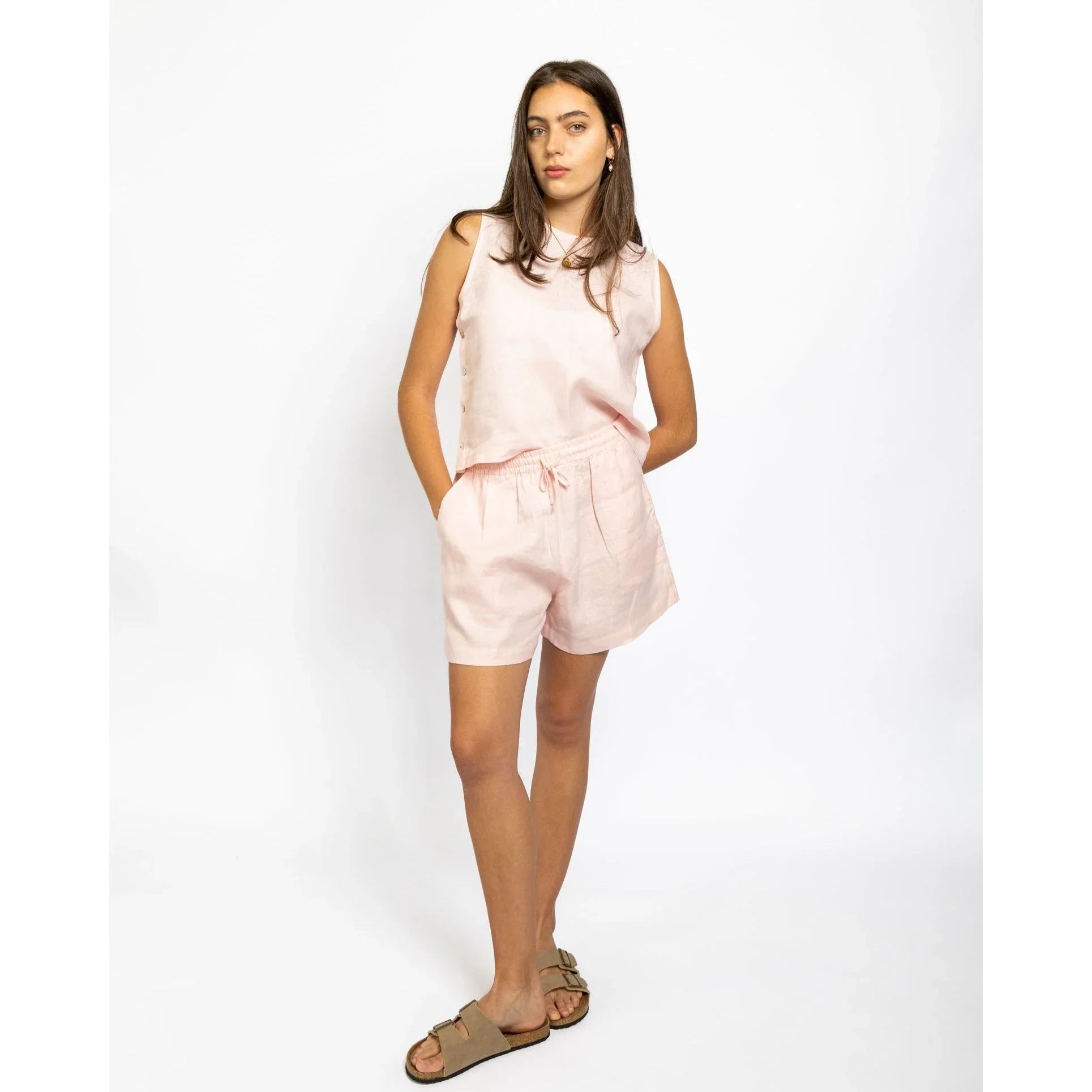 Woman wearing a pink sleeveless top and shorts set on a white background