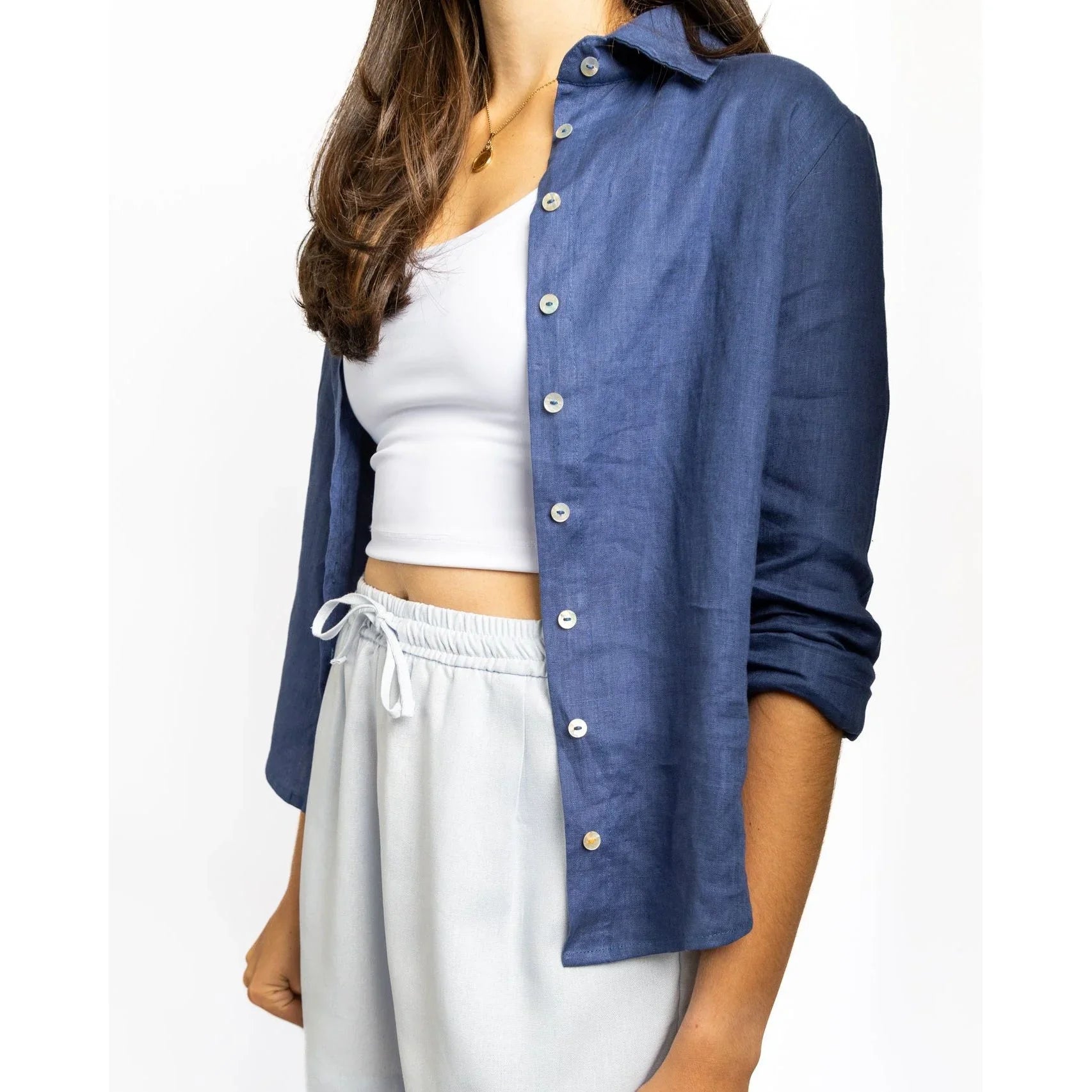 Person wearing a blue shirt over a white top and shorts on a white background