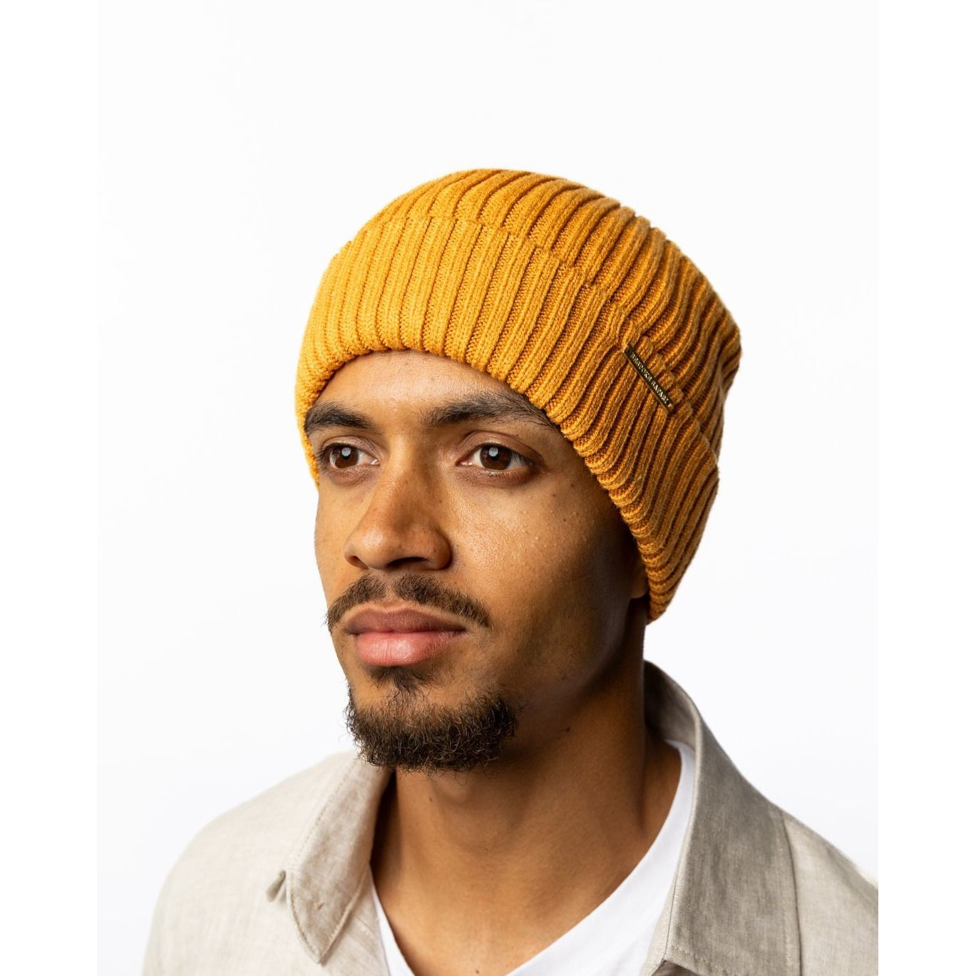Man wearing a mustard yellow beanie on a white background